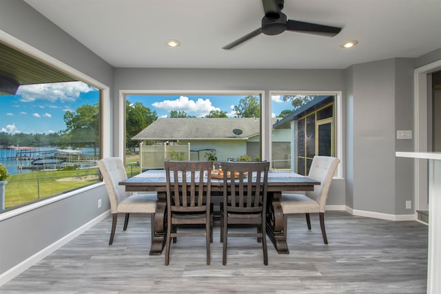 sunroom / solarium featuring a healthy amount of sunlight, a water view, and ceiling fan