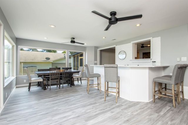 kitchen featuring light countertops, a peninsula, a kitchen bar, and a healthy amount of sunlight