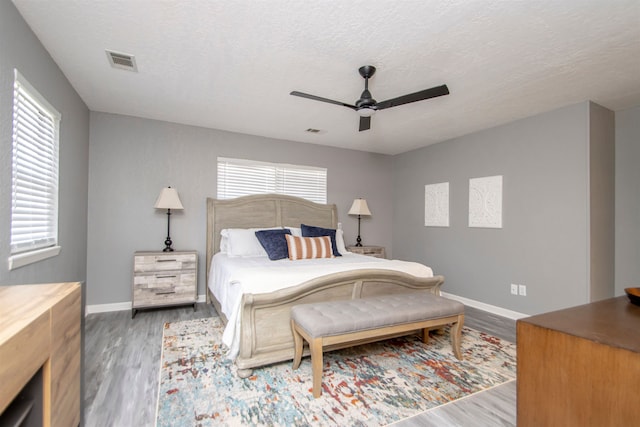 bedroom with baseboards, visible vents, multiple windows, and wood finished floors