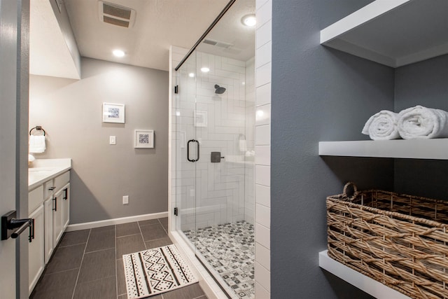 bathroom featuring a stall shower, baseboards, visible vents, tile patterned flooring, and vanity