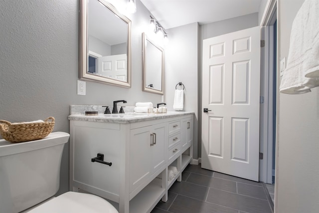 bathroom featuring double vanity, a sink, toilet, and tile patterned floors