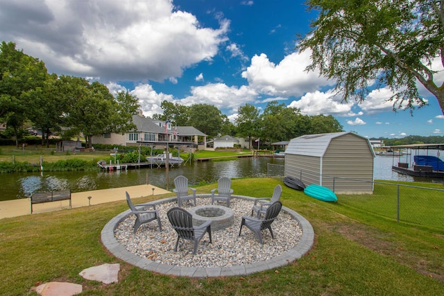 view of yard with a fire pit, a dock, a water view, and fence