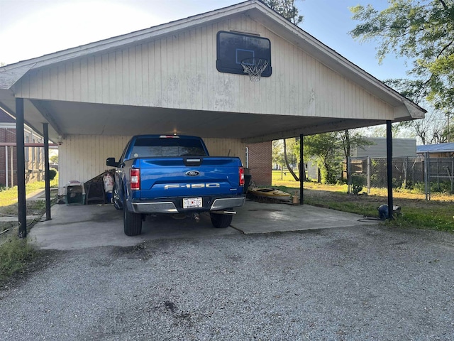 view of parking / parking lot with a carport, gravel driveway, and fence