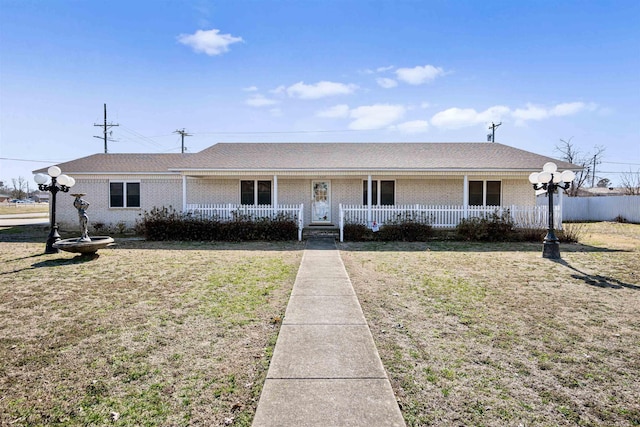 view of front of home with brick siding, roof with shingles, a front lawn, and fence
