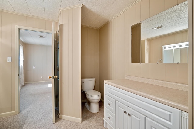 half bath featuring toilet, visible vents, baseboards, vanity, and crown molding