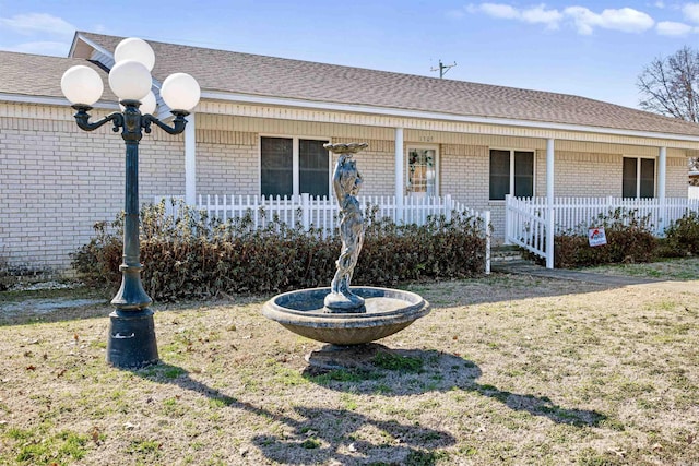 ranch-style home featuring brick siding, roof with shingles, and a front yard