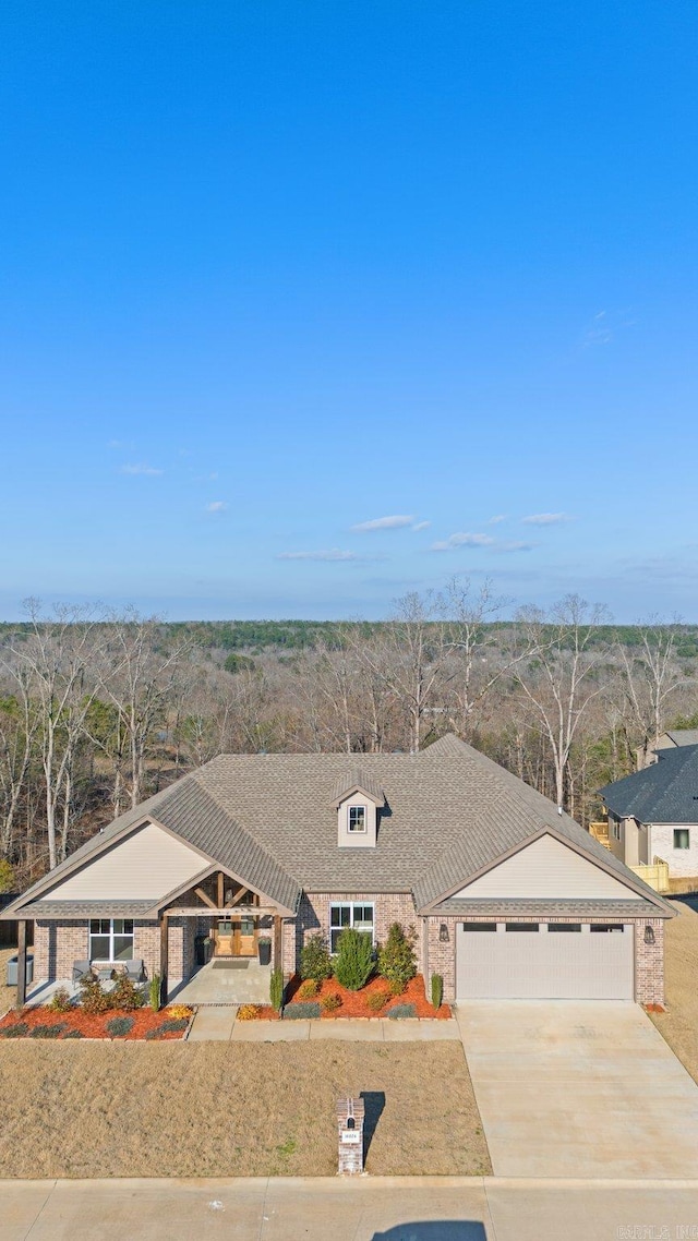 view of front of home with a garage, brick siding, driveway, and a shingled roof