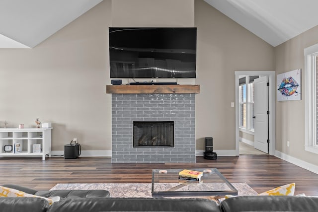 living area with baseboards, dark wood-style flooring, vaulted ceiling, and a tiled fireplace