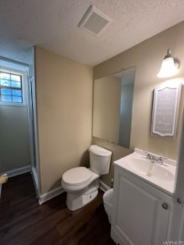 bathroom featuring baseboards, visible vents, toilet, wood finished floors, and vanity