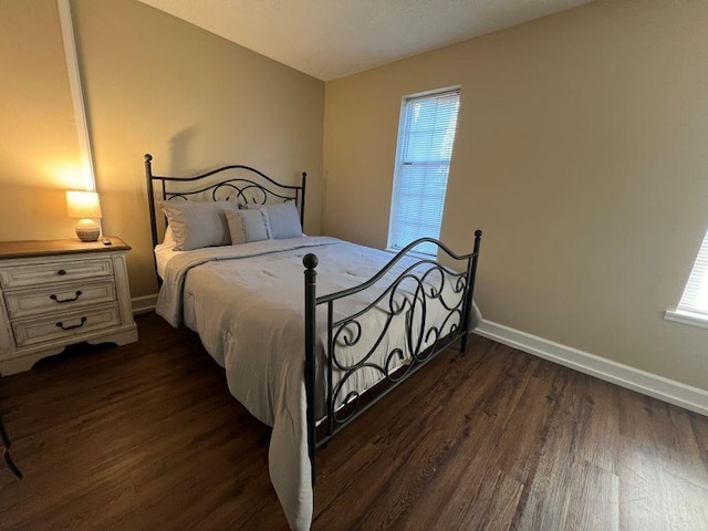 bedroom with dark wood-style floors, multiple windows, and baseboards