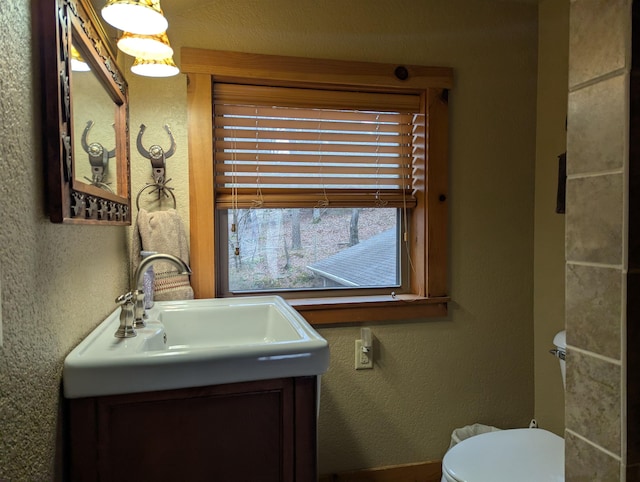 bathroom featuring a textured wall, vanity, and toilet