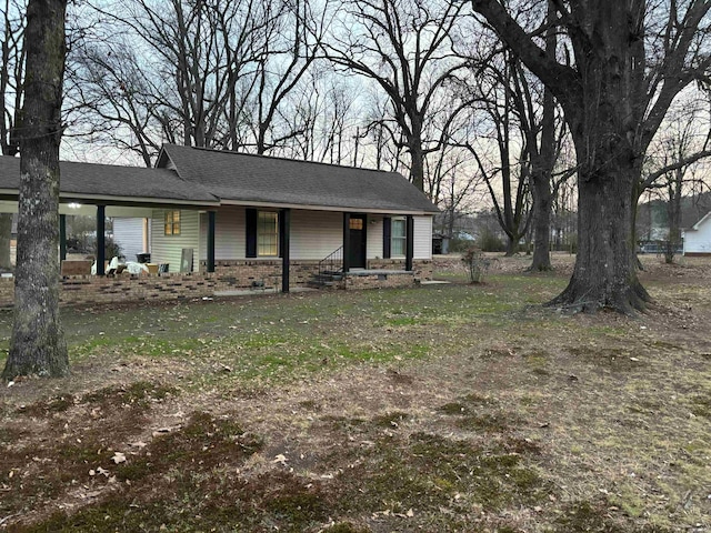 view of front of house with a front lawn, roof with shingles, and brick siding