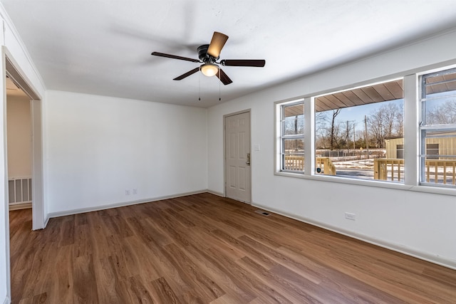 unfurnished room with ceiling fan, visible vents, baseboards, and wood finished floors