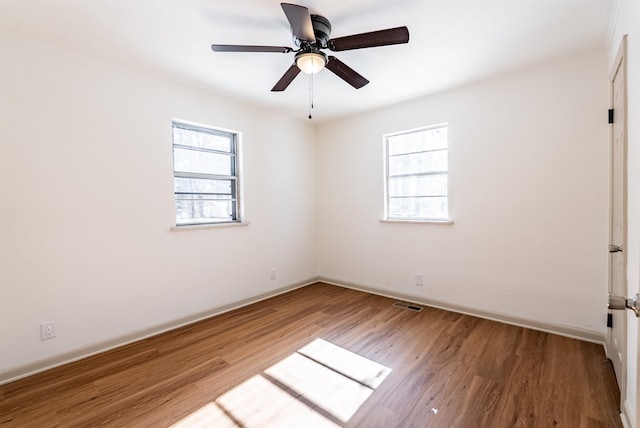 unfurnished room featuring visible vents, wood finished floors, and a wealth of natural light