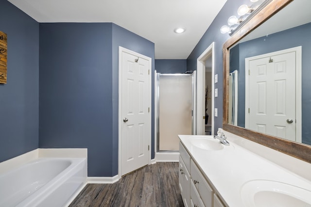 bathroom featuring a garden tub, a stall shower, a sink, and wood finished floors