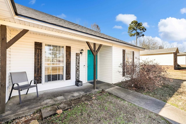 property entrance with covered porch and a shingled roof