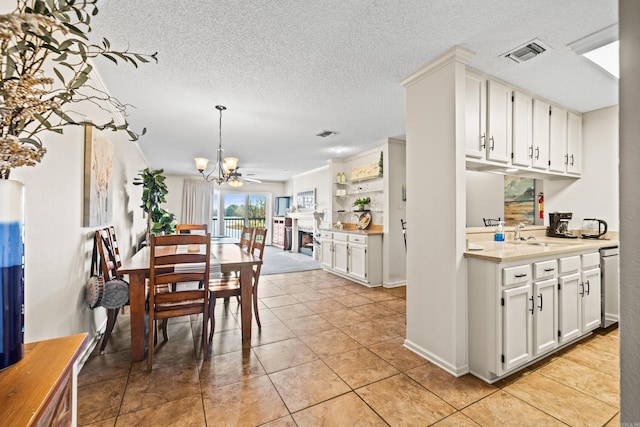 dining area with a fireplace, a notable chandelier, visible vents, light tile patterned flooring, and a textured ceiling