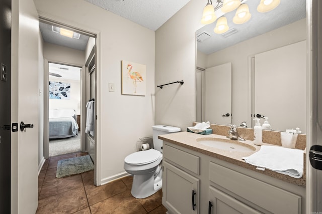 ensuite bathroom featuring a textured ceiling, connected bathroom, toilet, vanity, and tile patterned floors