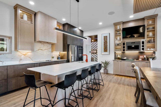 kitchen featuring stainless steel fridge with ice dispenser, modern cabinets, a center island, hanging light fixtures, and light countertops