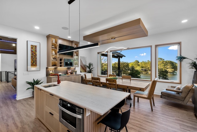 kitchen featuring open shelves, light wood-type flooring, decorative light fixtures, and a center island