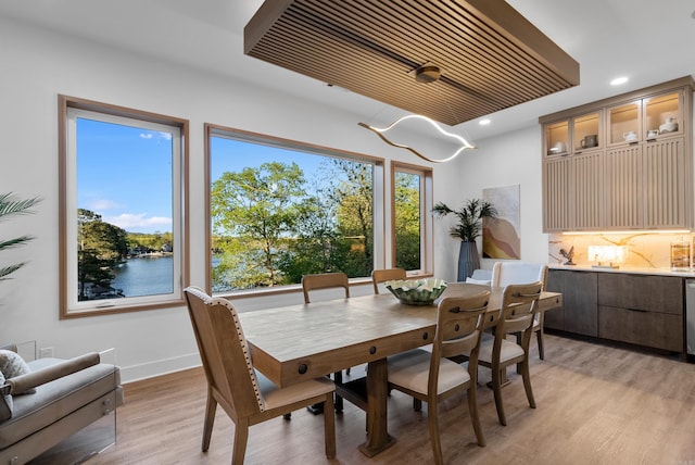 dining room with a water view, light wood-style flooring, baseboards, and recessed lighting