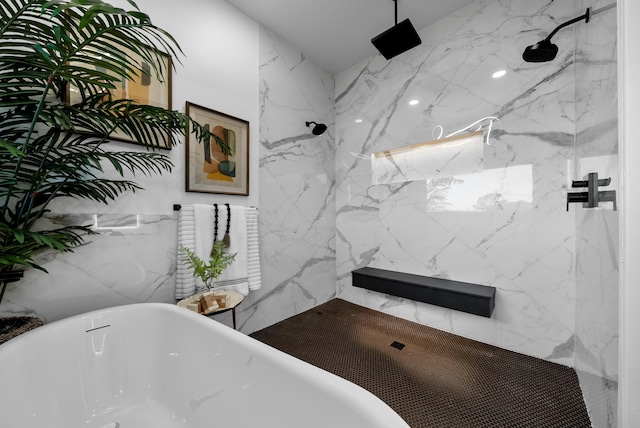 bathroom with a soaking tub, a marble finish shower, and stone wall