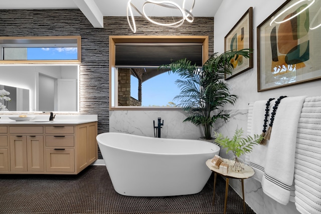 full bathroom featuring a chandelier, a freestanding bath, and vanity