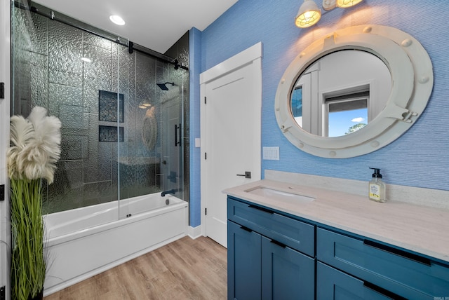 bathroom with shower / bath combination with glass door, wood finished floors, and vanity