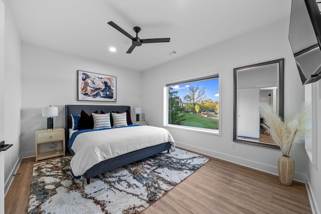 bedroom featuring baseboards, visible vents, ceiling fan, and wood finished floors