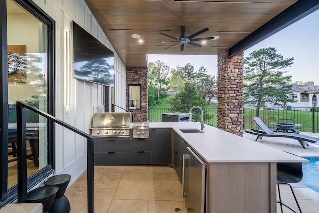 view of patio featuring an outdoor kitchen, area for grilling, ceiling fan, outdoor wet bar, and a sink