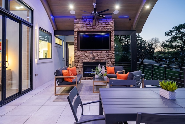 view of patio / terrace with outdoor dining area, ceiling fan, and an outdoor living space with a fireplace