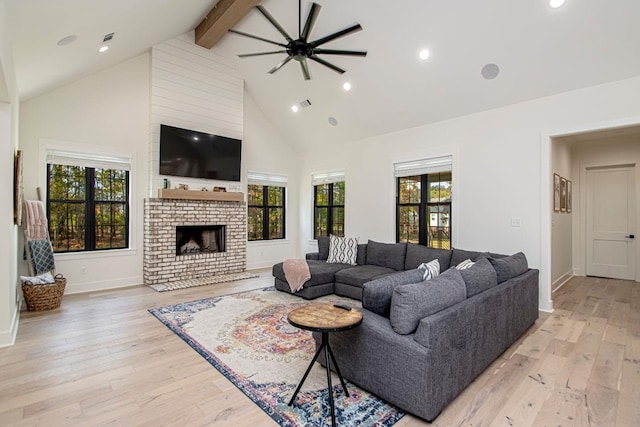 living area featuring baseboards, beamed ceiling, light wood-style floors, a fireplace, and high vaulted ceiling