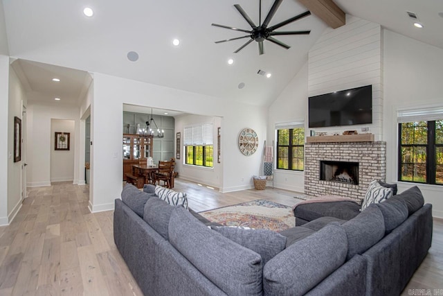 living room with light wood finished floors, beamed ceiling, an inviting chandelier, a fireplace, and high vaulted ceiling