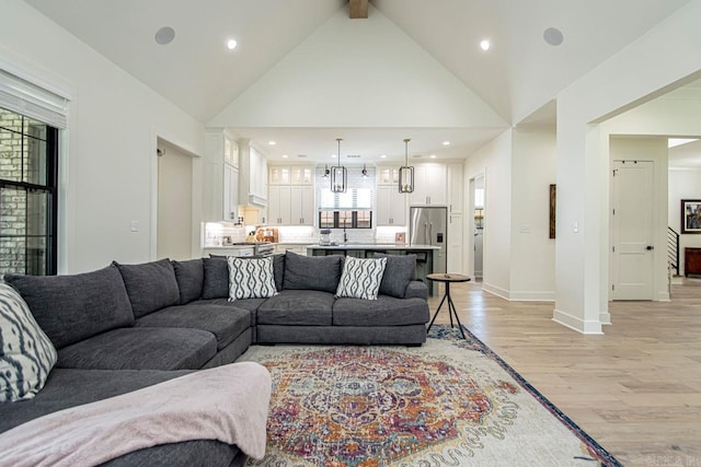 living area featuring light wood finished floors, baseboards, beamed ceiling, high vaulted ceiling, and recessed lighting