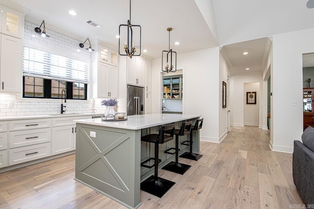 kitchen featuring white cabinets, glass insert cabinets, a center island, built in refrigerator, and light countertops