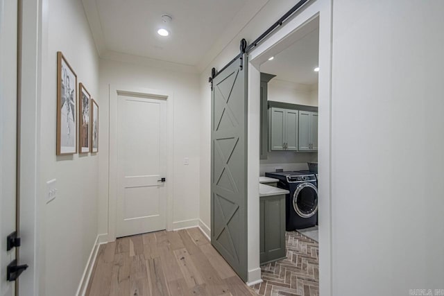 corridor with a barn door, crown molding, washer / clothes dryer, and baseboards