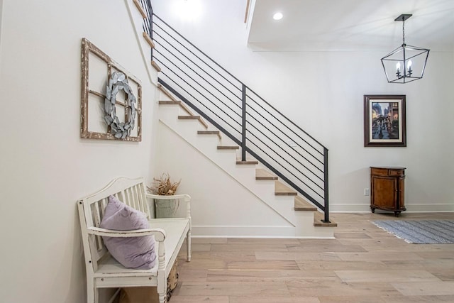 stairs with a notable chandelier, recessed lighting, wood finished floors, and baseboards