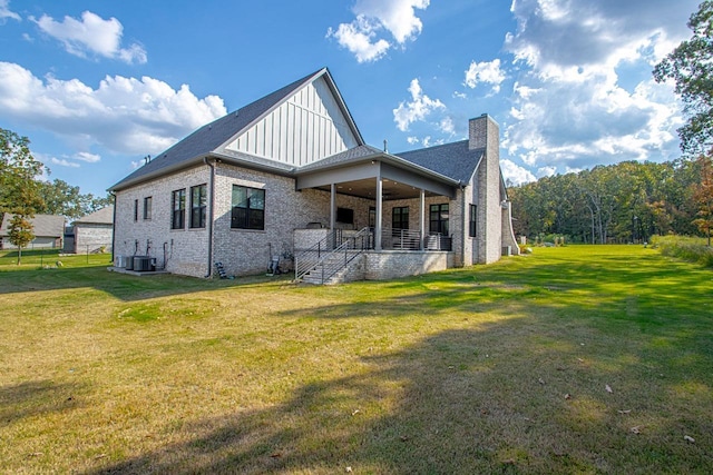 back of house featuring brick siding, a yard, a chimney, and central AC unit