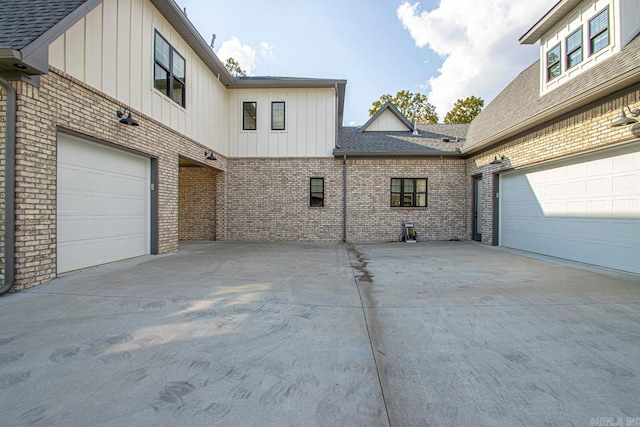 exterior space featuring a garage, brick siding, and board and batten siding