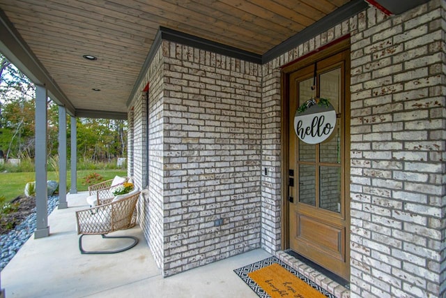 entrance to property with a porch and brick siding