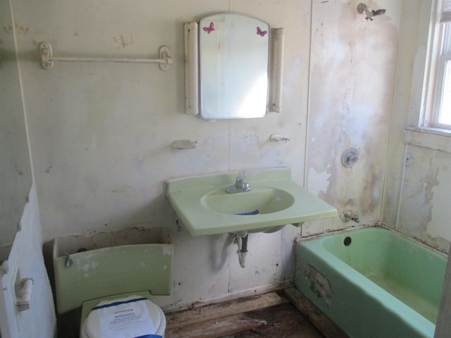 bathroom featuring toilet and a washtub