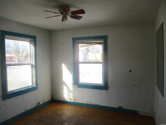 empty room featuring dark wood-type flooring, a wealth of natural light, and a ceiling fan