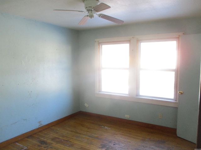 spare room featuring baseboards, dark wood finished floors, and a ceiling fan