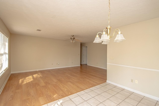 unfurnished room featuring a textured ceiling, ceiling fan with notable chandelier, visible vents, baseboards, and light wood finished floors