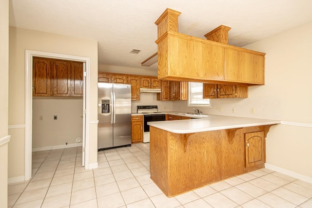 kitchen with brown cabinets, white range with electric cooktop, light countertops, stainless steel fridge, and a peninsula