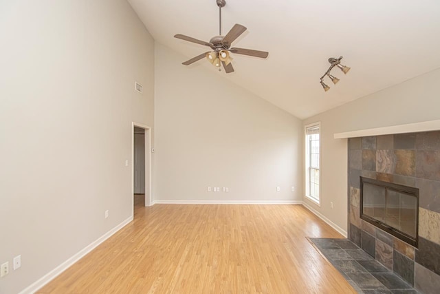 living room featuring light wood-type flooring, ceiling fan, baseboards, and a tile fireplace