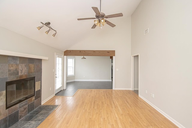 living area with a fireplace, lofted ceiling, ceiling fan, wood finished floors, and baseboards