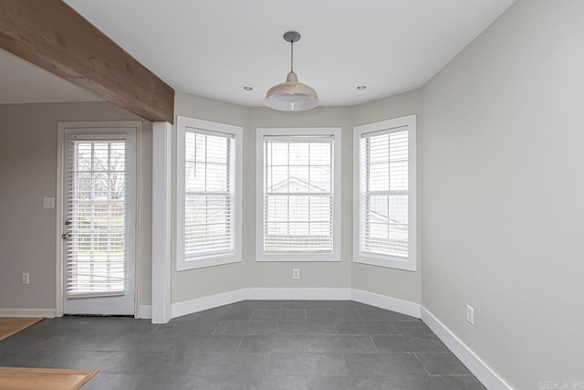 unfurnished dining area featuring plenty of natural light and baseboards