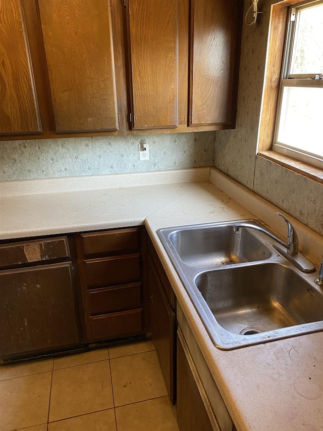 kitchen with light tile patterned floors, light countertops, a sink, and brown cabinets