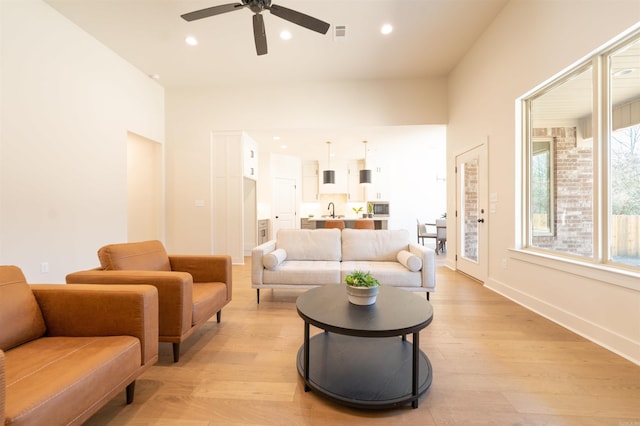 living area with light wood-type flooring, visible vents, baseboards, and recessed lighting